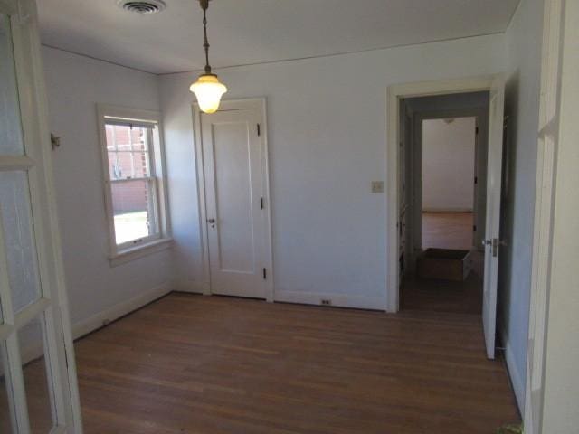 unfurnished dining area featuring baseboards, wood finished floors, and visible vents