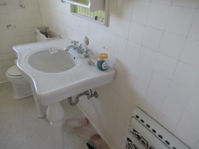 bathroom featuring a sink, toilet, and tile walls