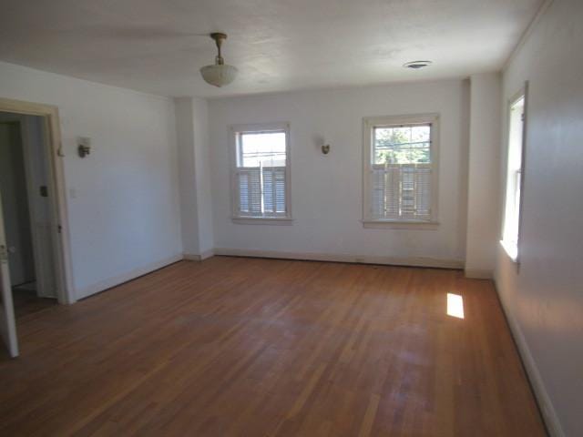 spare room with baseboards and wood finished floors