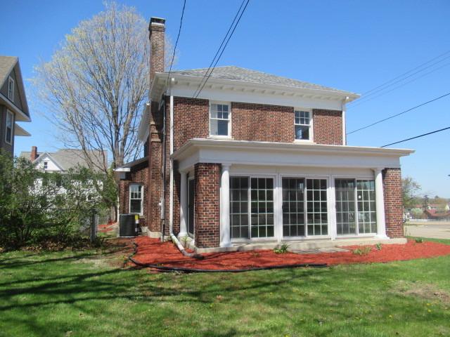 back of property with a yard, brick siding, central AC, and a chimney