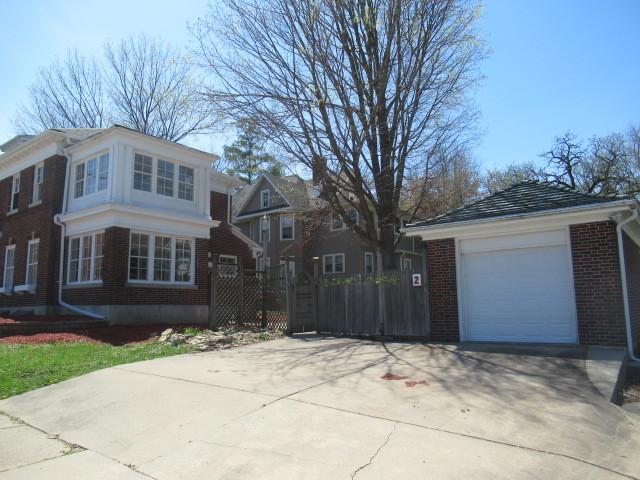 view of side of home with brick siding, fence, and concrete driveway
