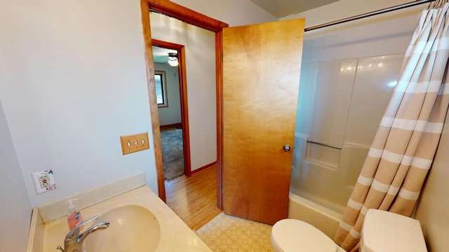 bathroom featuring a sink, shower / bathtub combination with curtain, and toilet