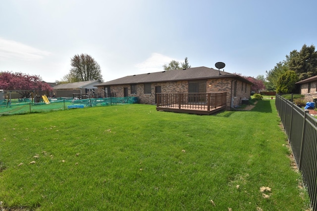 back of property featuring a lawn, brick siding, a wooden deck, and a fenced backyard