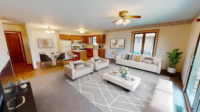 living area with visible vents, baseboards, ceiling fan, wallpapered walls, and light wood-type flooring