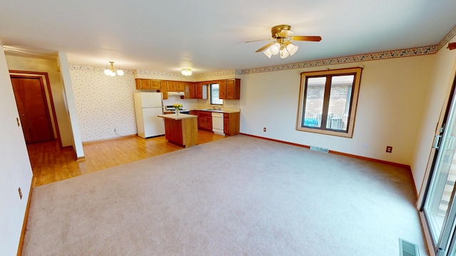 kitchen featuring a ceiling fan, open floor plan, light carpet, under cabinet range hood, and white appliances
