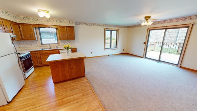 kitchen with a sink, brown cabinets, a kitchen island, and white appliances