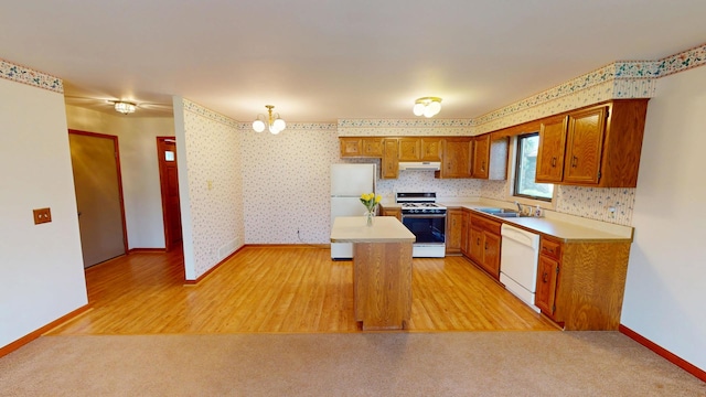 kitchen with white appliances, baseboards, light countertops, ventilation hood, and a sink
