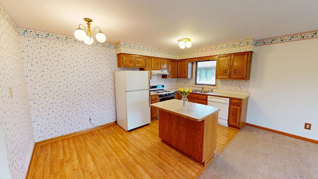 kitchen with exhaust hood, a notable chandelier, white appliances, light countertops, and wallpapered walls