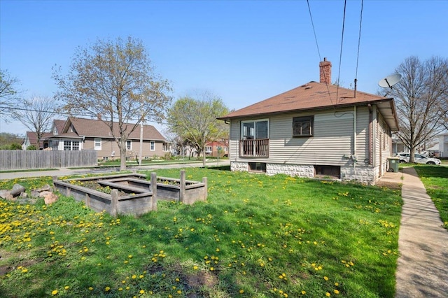 back of house with fence, a chimney, a yard, and a garden