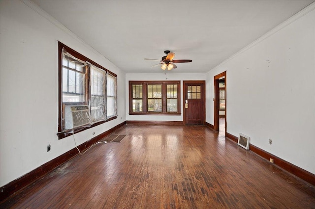 spare room with wood-type flooring, a ceiling fan, visible vents, and baseboards