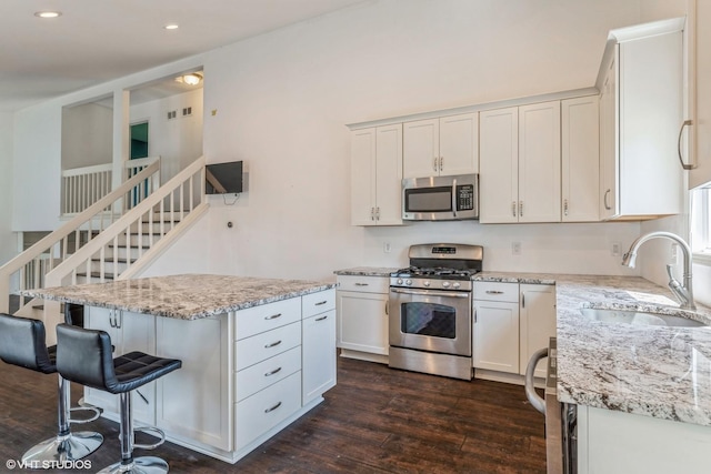 5116 Beechwood Ave, Gurnee, IL 60031 - kitchen with appliances with stainless steel finishes, a sink, dark wood-style floors, light stone countertops, and a kitchen breakfast bar