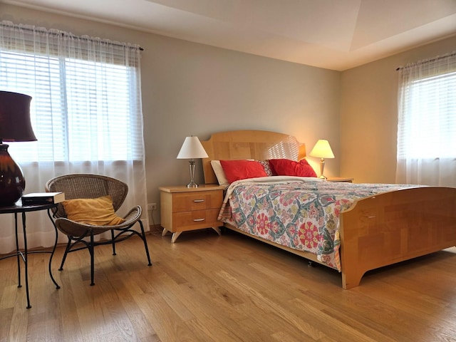 bedroom with multiple windows and wood finished floors