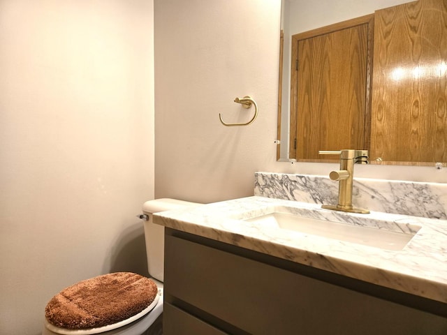 half bathroom featuring vanity and toilet
