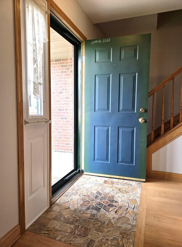 foyer with stairway, baseboards, and stone finish flooring
