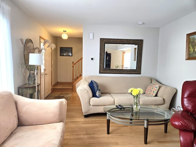 living area with stairs, baseboards, and wood finished floors