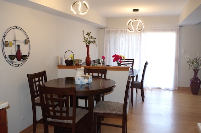 dining space with light wood-type flooring and a notable chandelier