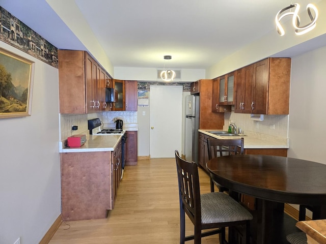 kitchen with freestanding refrigerator, backsplash, gas range oven, and light countertops