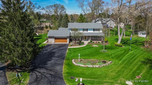 3518 James Way, Johnsburg, IL 60051 - view of front of house with a porch, driveway, stone siding, a front yard, and an attached garage