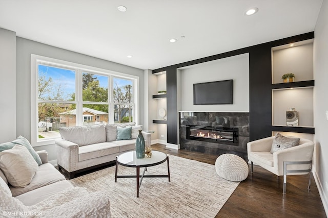 living area with recessed lighting, baseboards, a glass covered fireplace, and wood finished floors