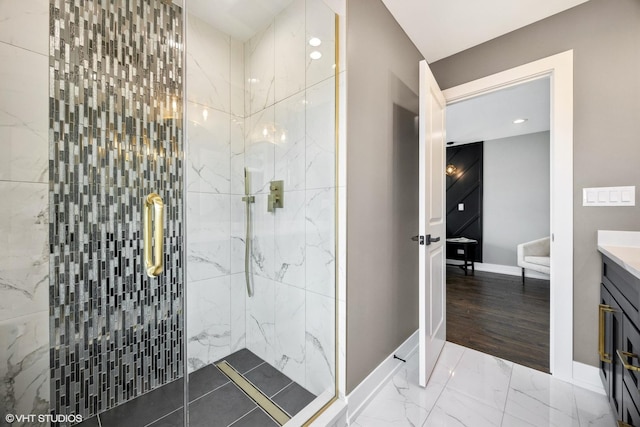 bathroom with a marble finish shower, baseboards, and vanity