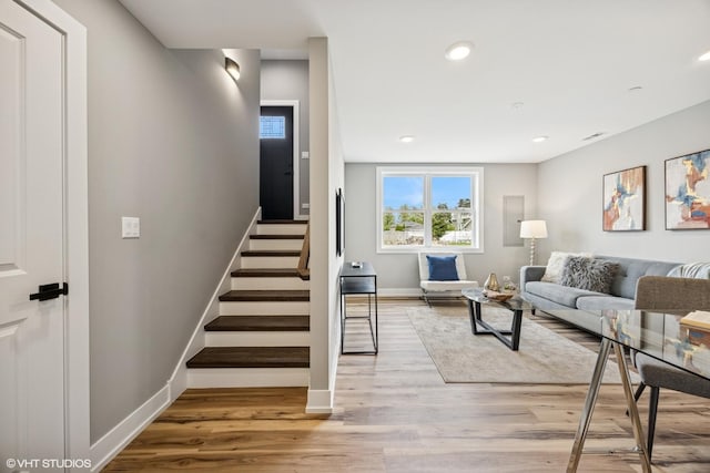 living area with stairs, baseboards, light wood-style flooring, and recessed lighting