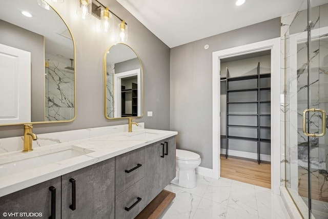 bathroom featuring a marble finish shower, marble finish floor, a spacious closet, and a sink