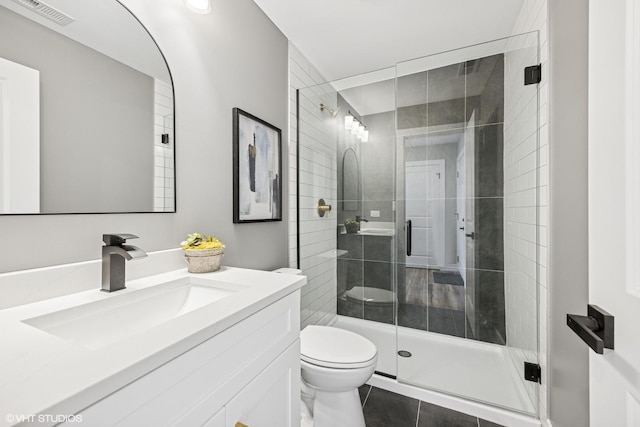 bathroom with toilet, tile patterned floors, visible vents, a shower stall, and vanity