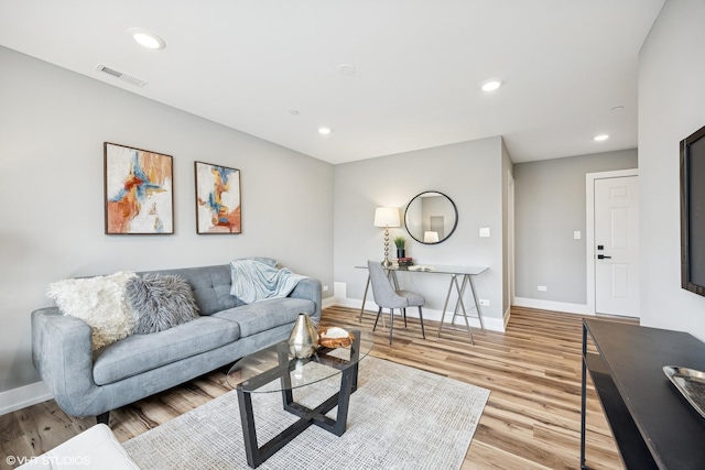 living room with light wood finished floors, visible vents, baseboards, and recessed lighting