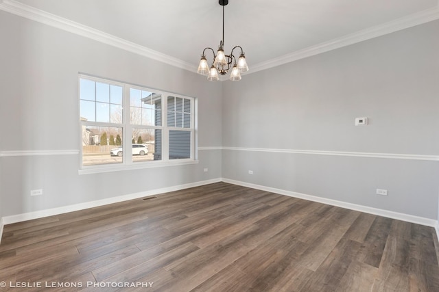 empty room with dark wood finished floors, an inviting chandelier, ornamental molding, and baseboards