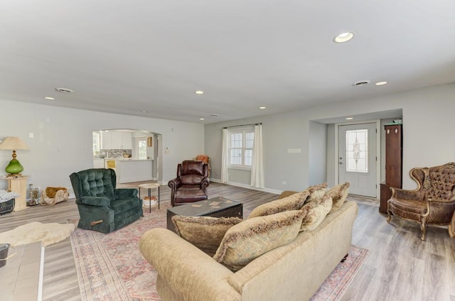 living area featuring light wood-type flooring, arched walkways, and recessed lighting
