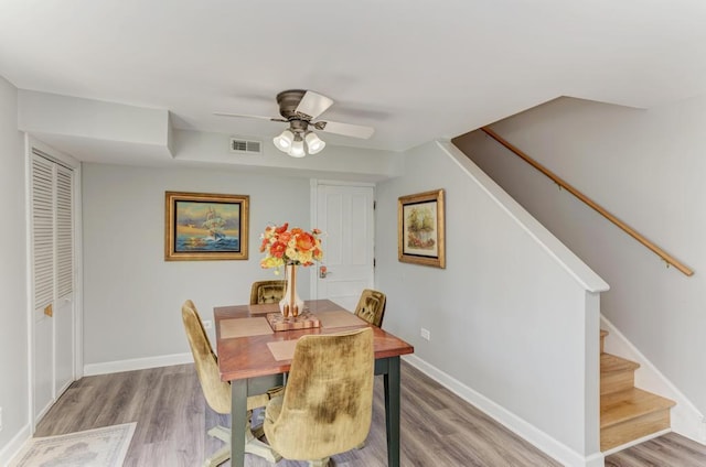 dining area featuring stairs, wood finished floors, ceiling fan, baseboards, and visible vents