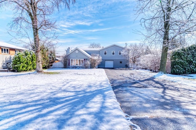view of front of home with an attached garage, a chimney, and aphalt driveway