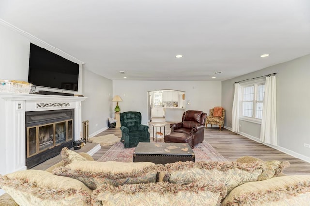 living room featuring baseboards, a glass covered fireplace, wood finished floors, and recessed lighting