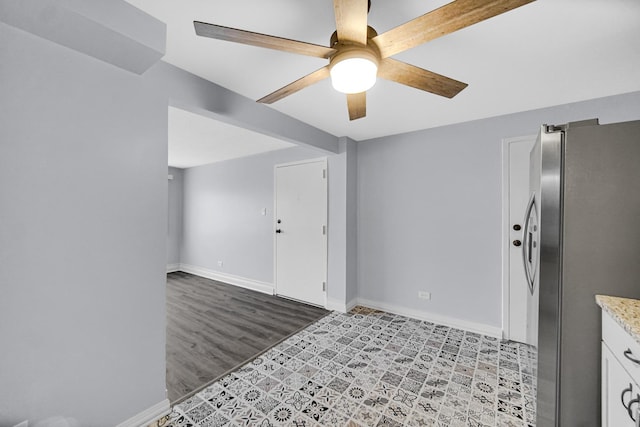 kitchen featuring ceiling fan, light wood finished floors, freestanding refrigerator, baseboards, and white cabinetry