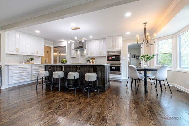 kitchen featuring appliances with stainless steel finishes, a kitchen breakfast bar, decorative backsplash, and white cabinetry