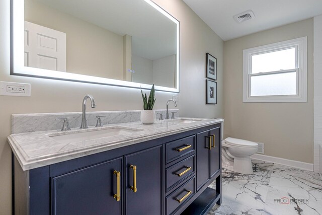 full bath featuring double vanity, toilet, a sink, and marble finish floor