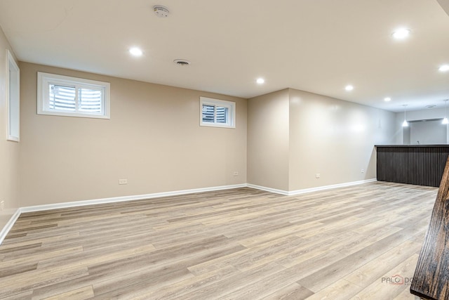 basement with visible vents, light wood-type flooring, baseboards, bar area, and recessed lighting