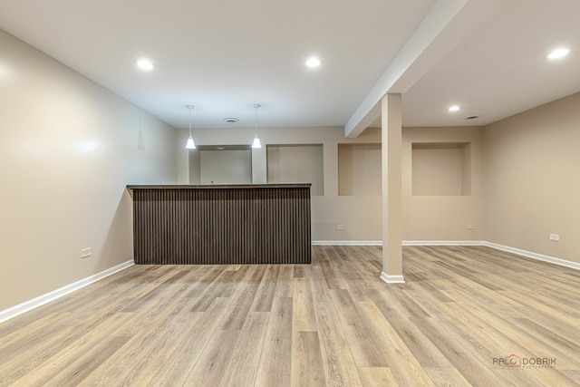 bar with baseboards, a dry bar, light wood finished floors, and hanging light fixtures