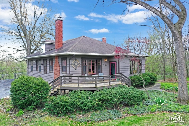 view of front of property featuring a chimney, a shingled roof, and a wooden deck