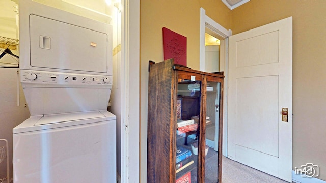 washroom with carpet flooring, stacked washing maching and dryer, and laundry area
