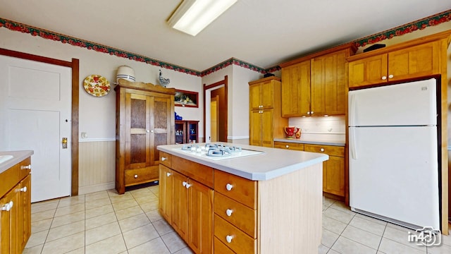 kitchen featuring white appliances, light tile patterned flooring, light countertops, and a kitchen island