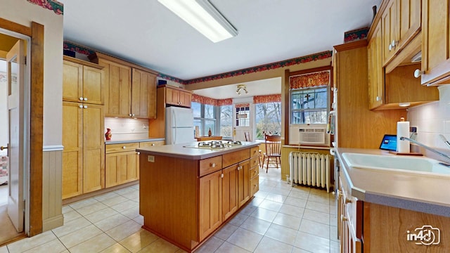 kitchen with radiator, a sink, light tile patterned flooring, a center island, and white appliances