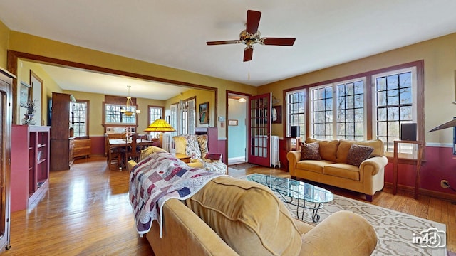 living room with baseboards, wood finished floors, ceiling fan with notable chandelier, and plenty of natural light