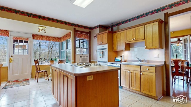 kitchen featuring a center island, white appliances, light countertops, and a sink