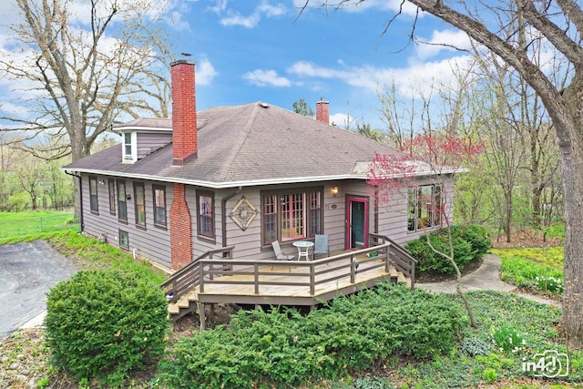 rear view of property with a chimney, a shingled roof, and a deck