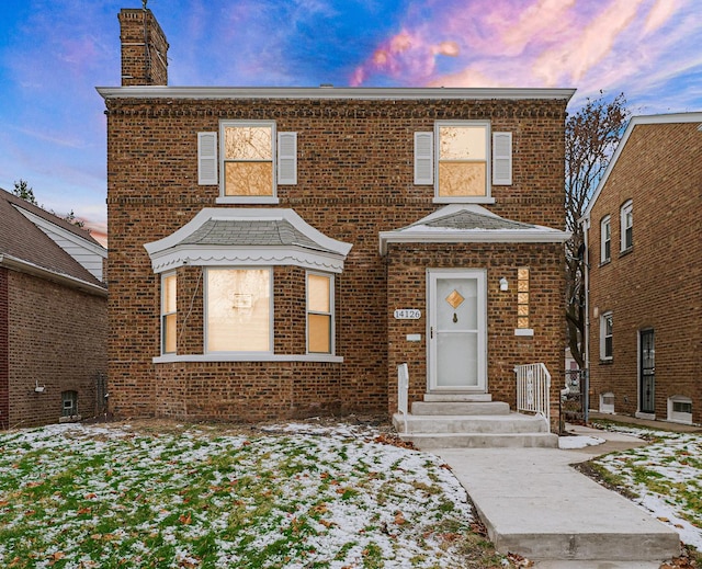view of front of house featuring a chimney and brick siding