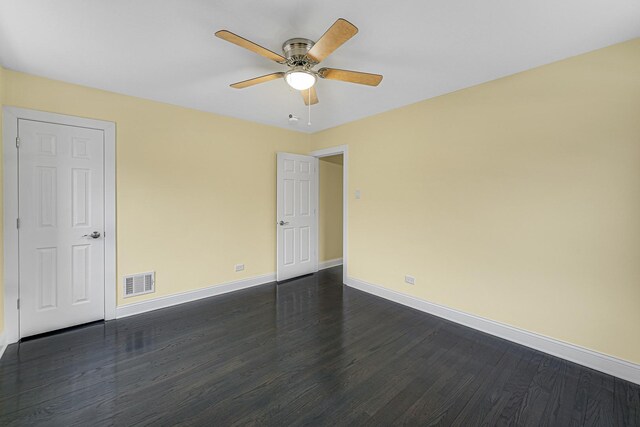 unfurnished room with dark wood-type flooring, visible vents, a ceiling fan, and baseboards