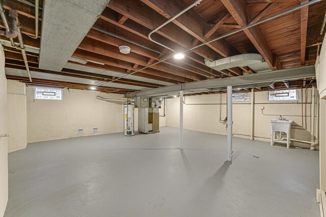 below grade area with water heater, heating unit, and a sink