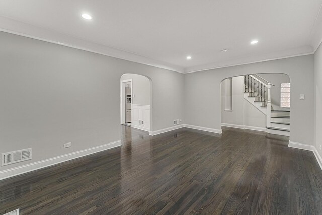 spare room with stairway, visible vents, arched walkways, crown molding, and dark wood-style flooring