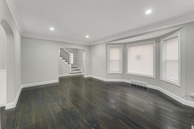 unfurnished living room with arched walkways, visible vents, baseboards, and dark wood-style flooring